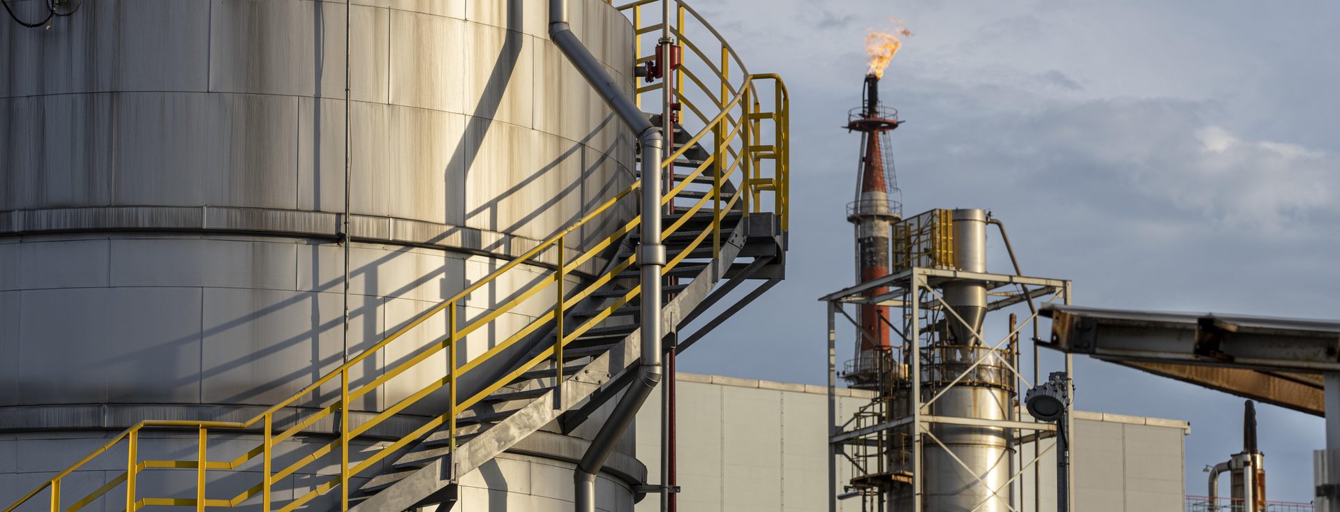 Refinaria de óleo e gás com tanques e flare ao pôr do sol